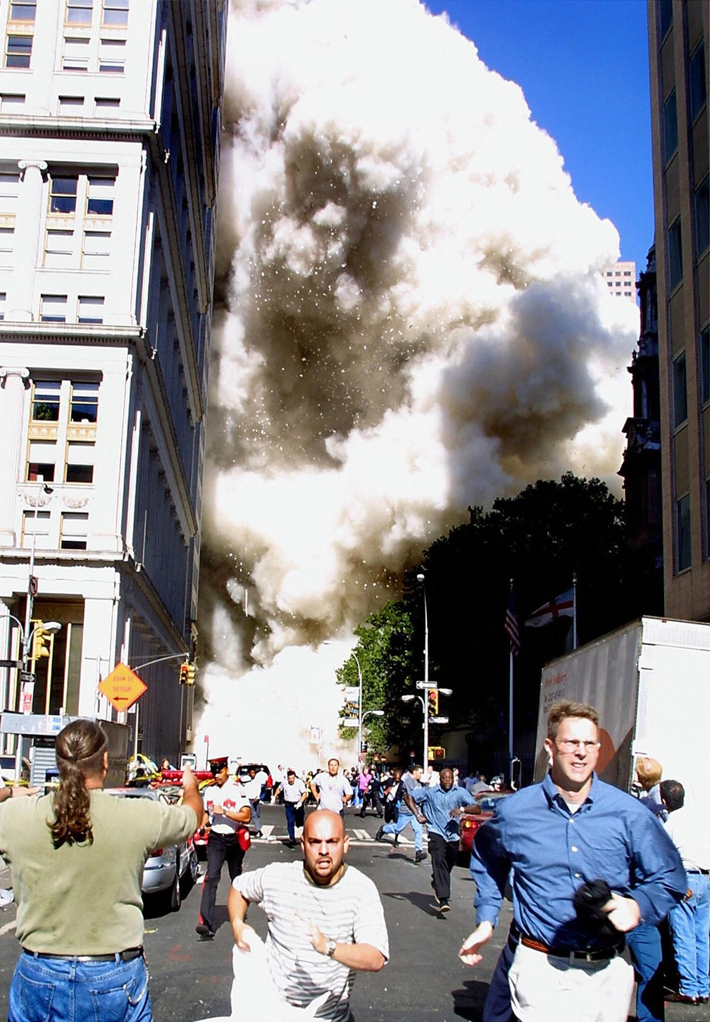 Pedestres correm enquanto uma das torres do World Trade Center vem abaixo e uma nuvem de poeira e destroços se aproxima em Nova York, no dia 11 de setembro de 2001 - Foto: Doug Kanter/AFP/Arquivo