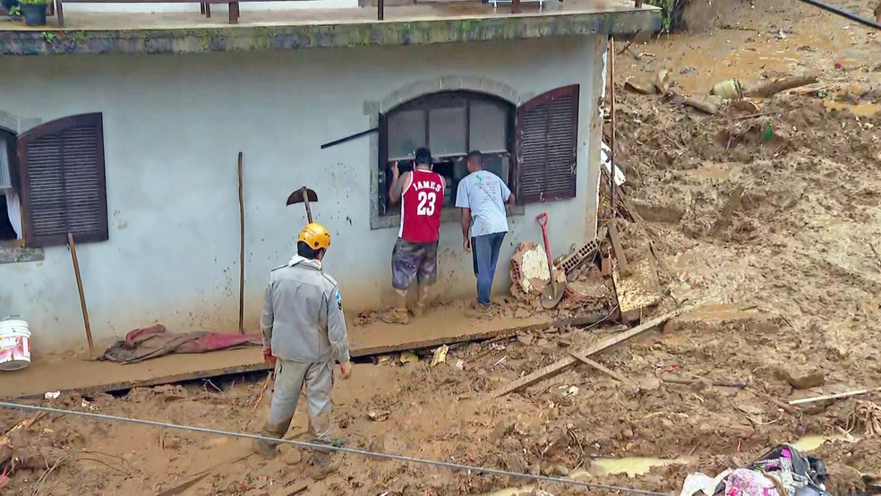 Socorristas buscam vítimas na janela do segundo andar de um prédio - o primeiro foi soterrado - Foto: Reprodução/TV Globo