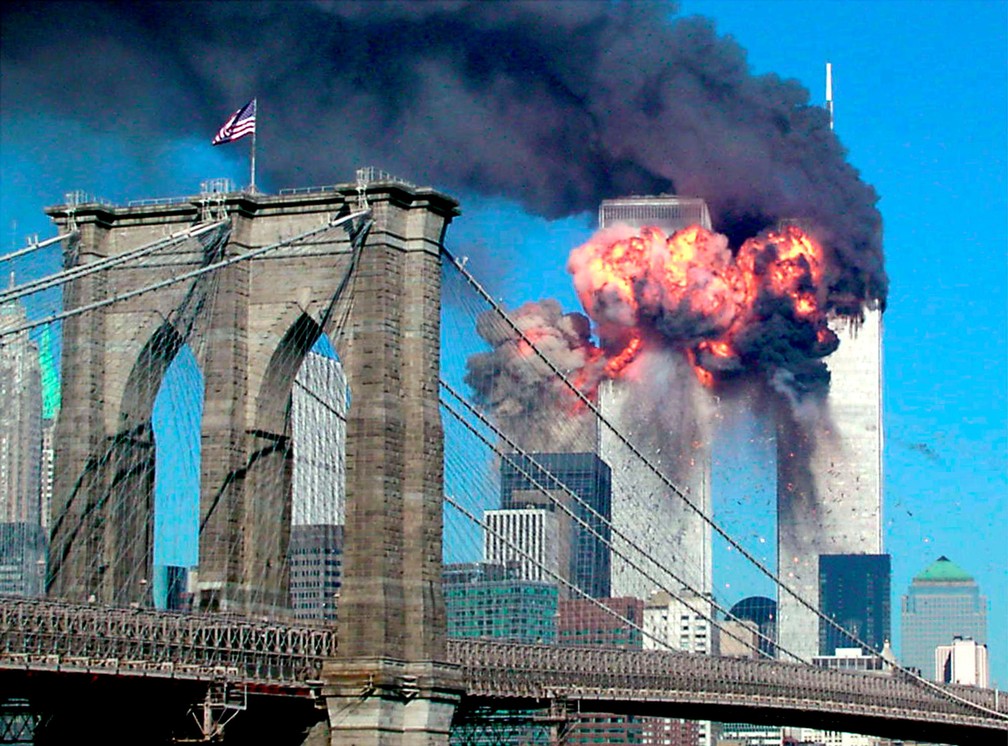 Por trás da Ponte do Brooklyn, a explosão do segundo avião a atingir o World Trade Center é vista de longe em Nova York durante o ataque terrorista em 11 de setembro de 2001 - Foto: Sara K. Schwittek/Reuters/Arquivo