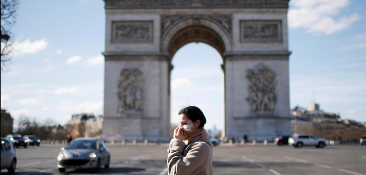 Uma mulher usando uma máscara protetora caminha perto do Arco do Triunfo enquanto a França enfrenta um surto de doença por coronavírus, em Paris