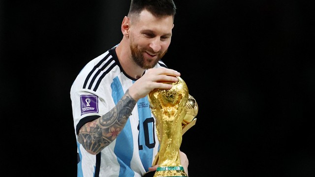 Lionel Messi passando a mão na taça da Copa do Mundo