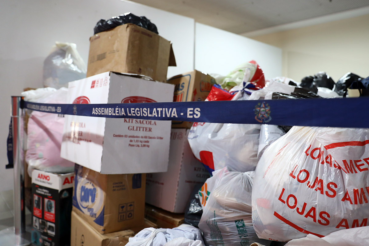 Diversas sacolas e caixas com roupas e outros donativos reunidas em espaço da Assembleia 