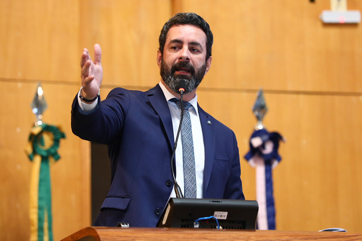 Homem de barca e cabelos castanhos veste terno azul