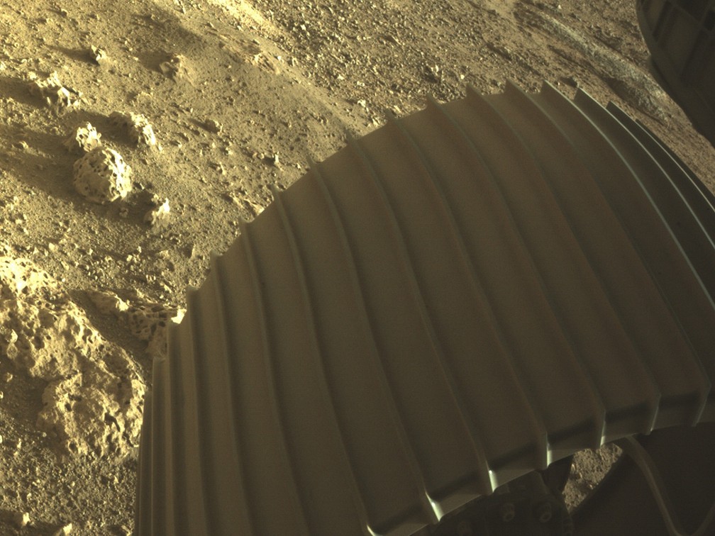 Uma das rodas do robô Perseverance, da Nasa, tocando o solo de Marte. - Foto: NASA