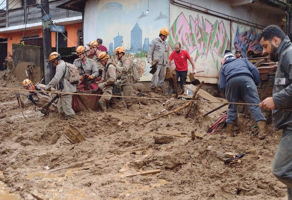 Corpo sendo retirado, na manhã desta quarta (16), da barreira que atingiu o Morro da Oficina, em Petrópolis - Foto: Alexandre Kapiche/g1